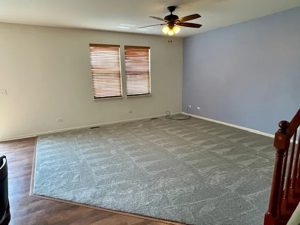 an empty room with windows and fan