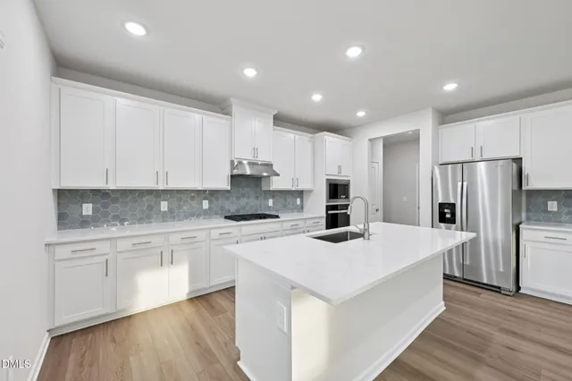 a kitchen with stainless steel appliances white cabinets and a stove top oven