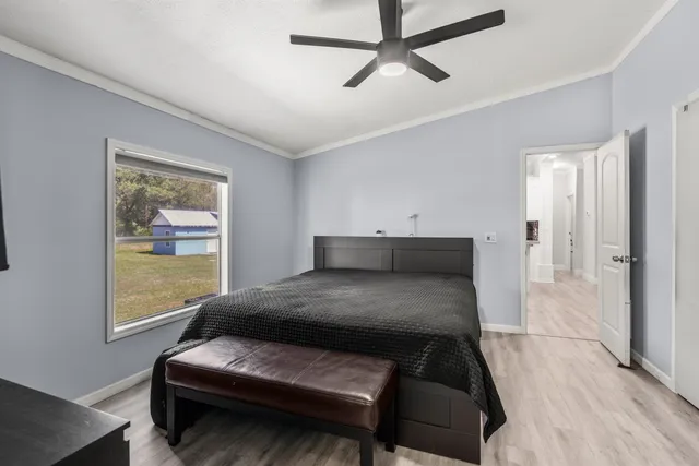 a bedroom with a bed window and walk in closet with wooden floor