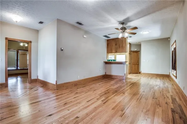 a view of empty room with wooden floor and fan
