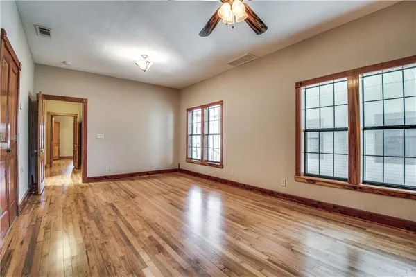 a view of an empty room with a window and wooden floor