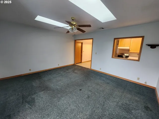 en empty room with windows and ceiling fan
