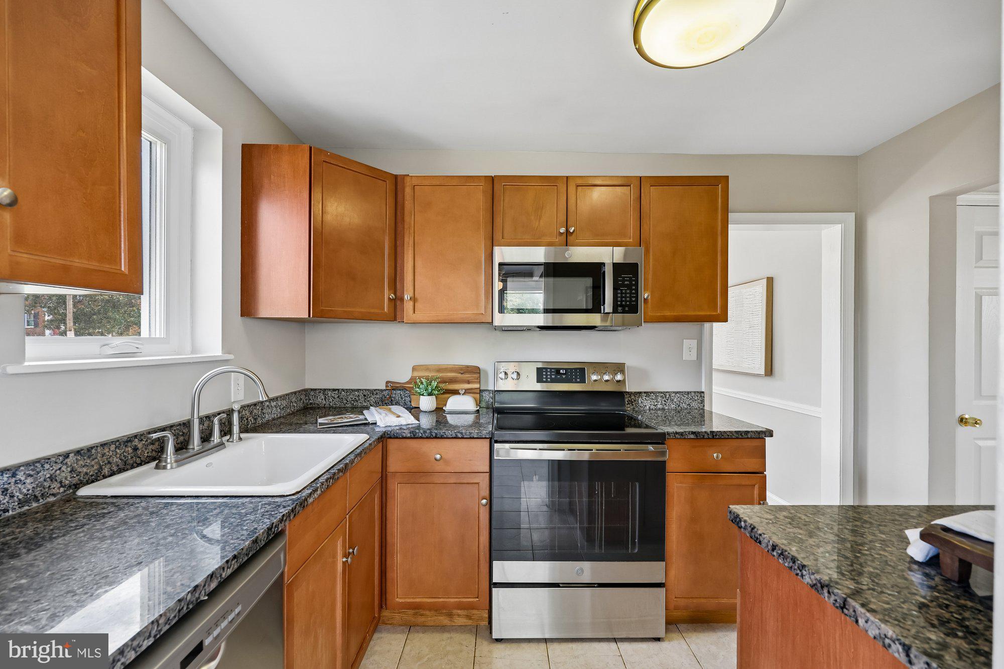 2613 Elnora Street Silver Spring, MD 20902 - Photo 13 of 54 a kitchen with stainless steel appliances granite countertop a stove a sink and a microwave