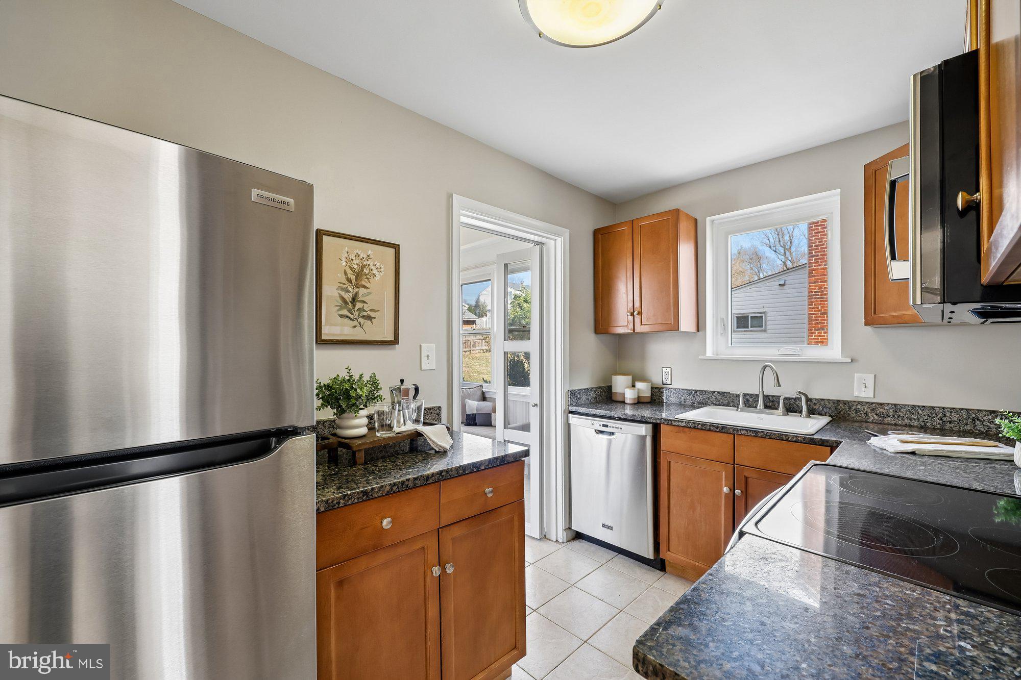 2613 Elnora Street Silver Spring, MD 20902 - Photo 14 of 54 a kitchen with stainless steel appliances granite countertop a refrigerator a sink dishwasher a stove and a dining table with wooden floor