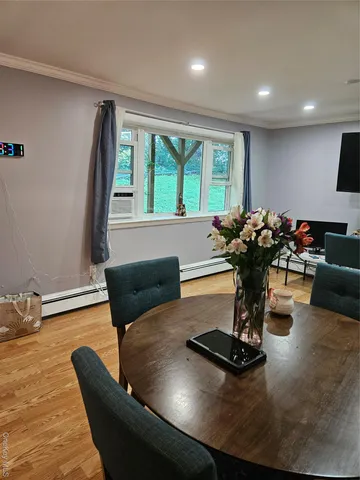 a living room with furniture hard wood floor and a floor to ceiling window