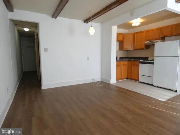a view of a refrigerator in kitchen and an empty room