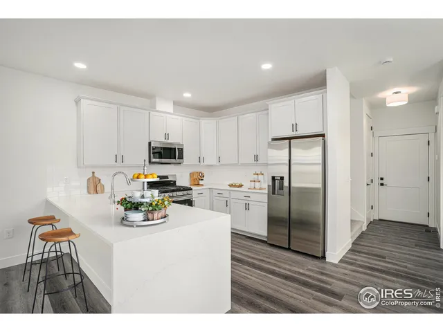 a kitchen with a refrigerator a stove top oven a sink dishwasher and white cabinets with wooden floor