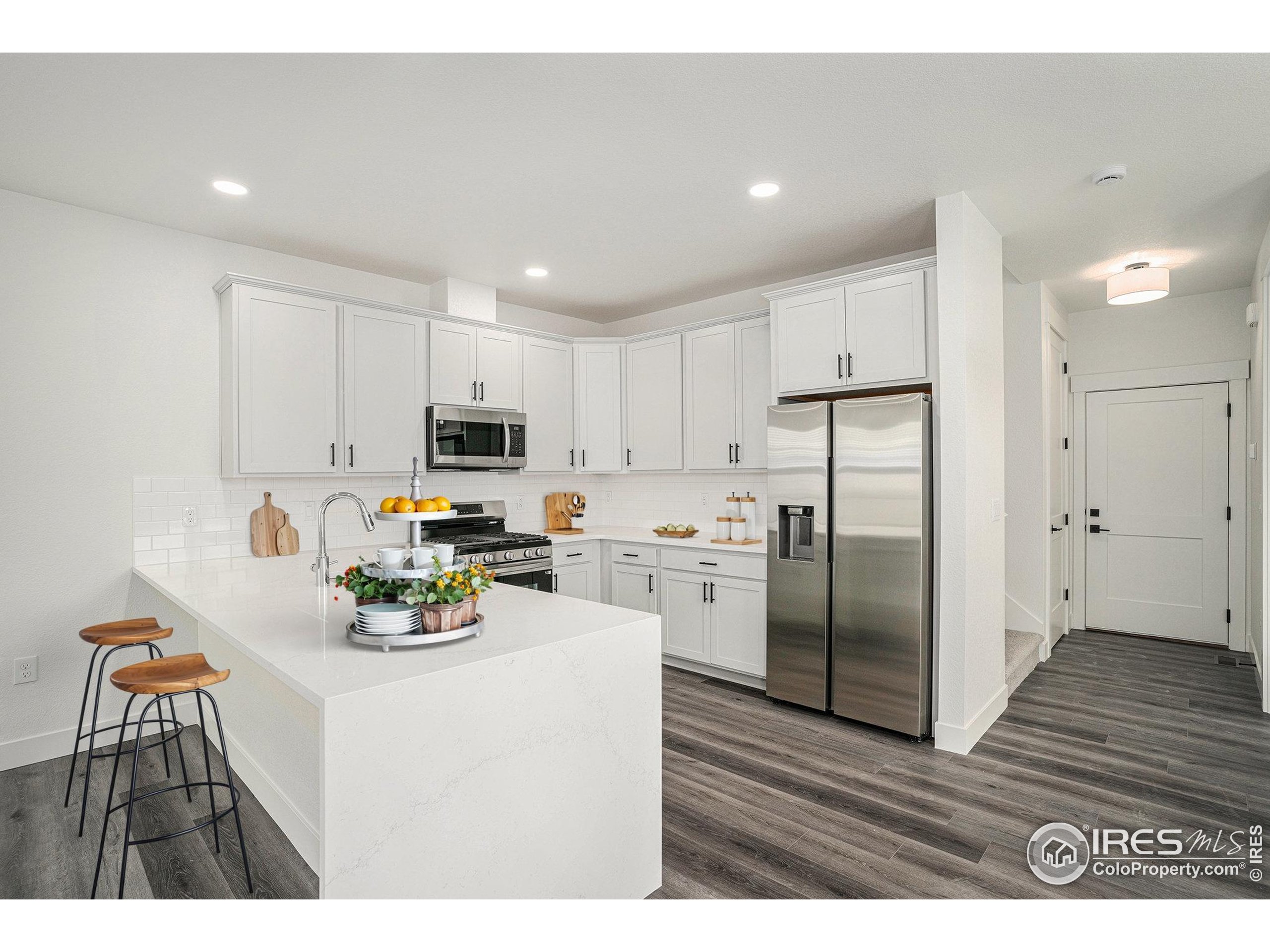 5049 Avon Avenue Loveland, CO 80538 - Photo 4 of 10 a kitchen with a refrigerator a stove top oven a sink dishwasher and white cabinets with wooden floor