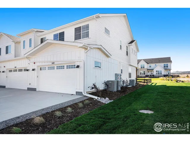 a view of a white house with a big yard potted plants and large tree