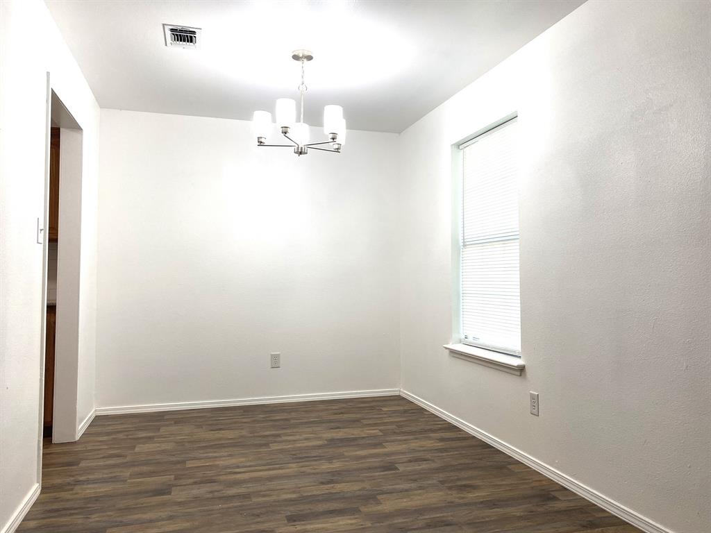 505 Red Springs Avenue Mount Pleasant, TX 75455 - Photo 3 of 9 Empty room featuring a chandelier and dark wood-style floors