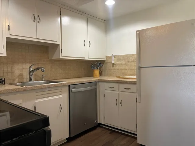 a kitchen with stainless steel appliances granite countertop a refrigerator a stove top oven a sink and dishwasher