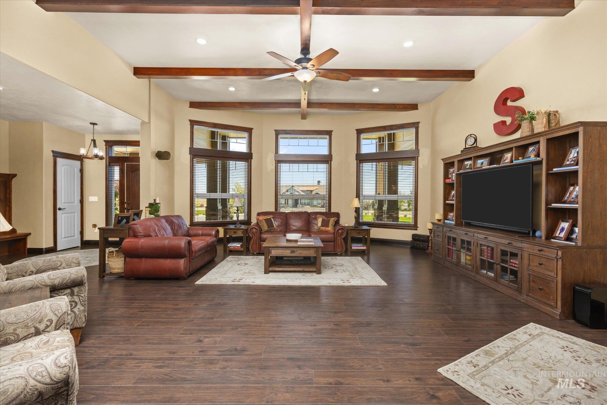 Vaulted ceiling with exposed wood beams, wood-finish flooring, built-in entertainment center, recessed lighting, and a ceiling fan
