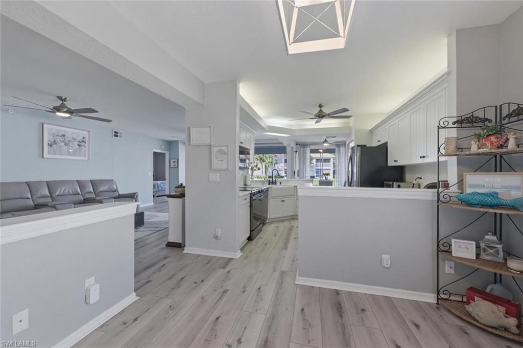 6899 Rain Lily Road, Unit 103 Naples, FL 34109 - Photo 39 of 39 Kitchen with a ceiling fan, white cabinets, and open floor plan