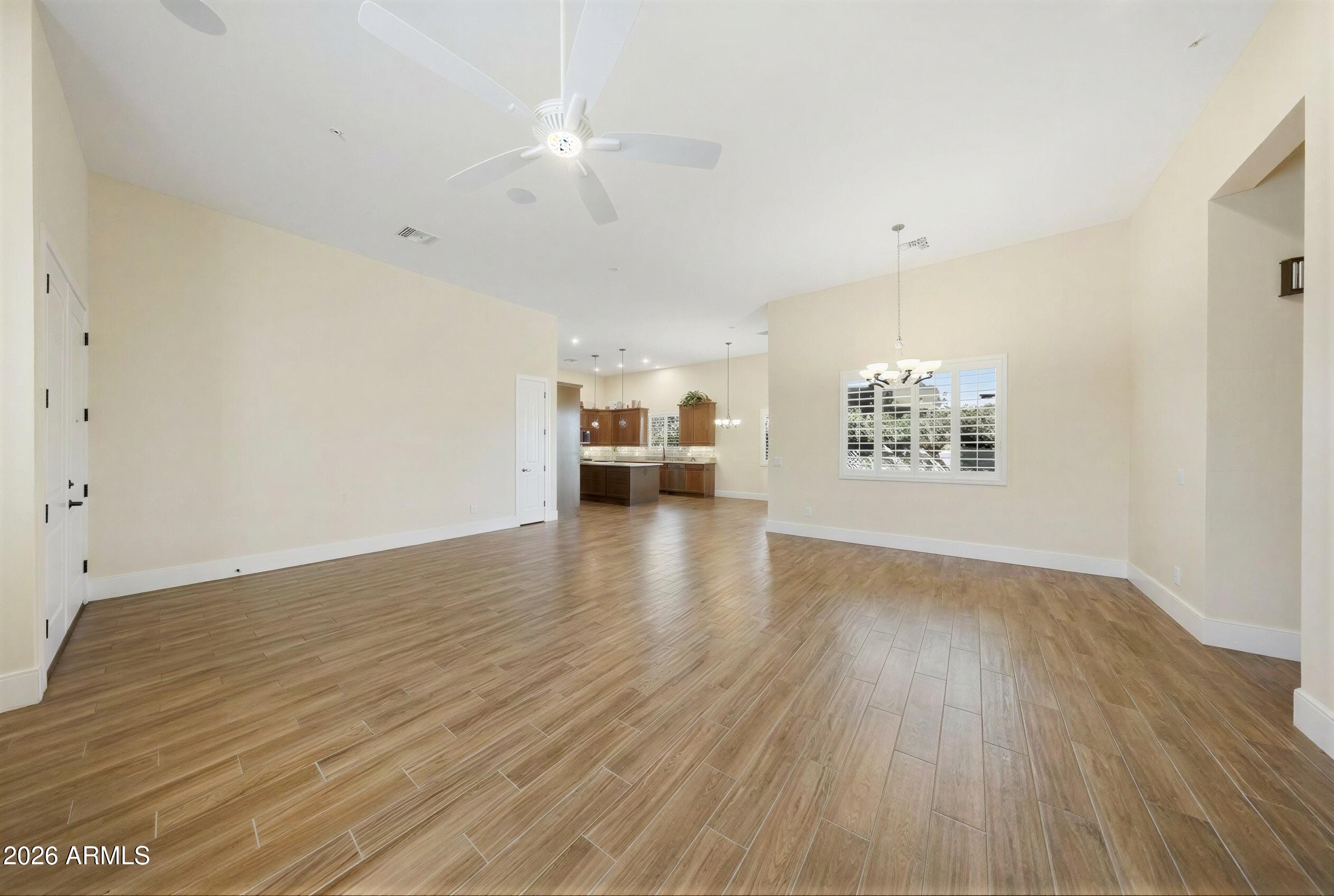 8974 North 8th Lane Phoenix, AZ 85021 - Photo 4 of 29 an empty room with wooden floor chandelier fan and windows