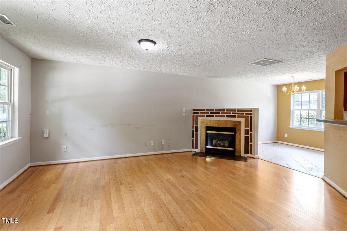 4221 Tensity Drive Raleigh, NC 27604 - Photo 4 of 31 an empty room with wooden floor fireplace and windows