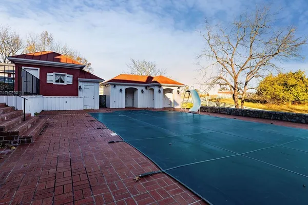 an aerial view of a house with swimming pool and a yard