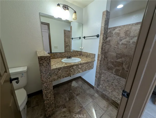 a bathroom with a granite countertop sink a mirror and shower