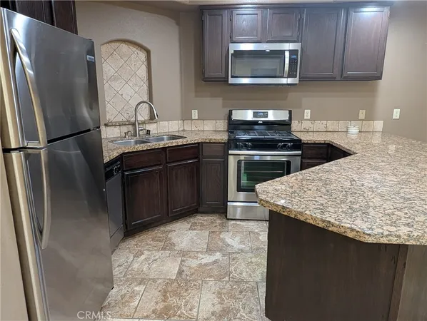 a kitchen with granite countertop a refrigerator stove and sink