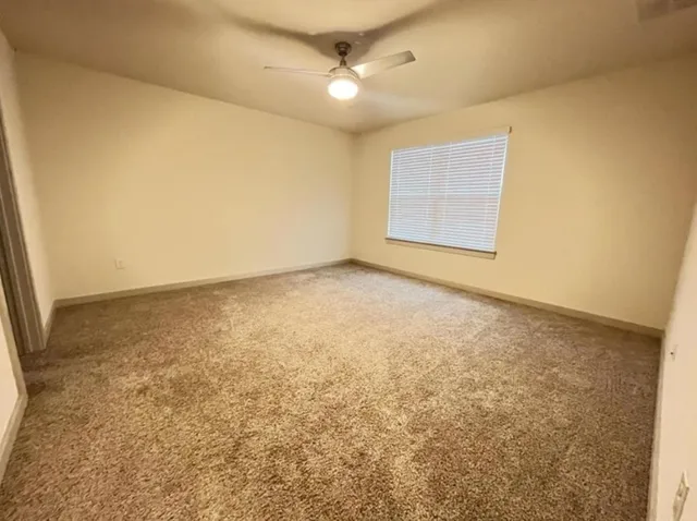 an empty room with ceiling fan and window