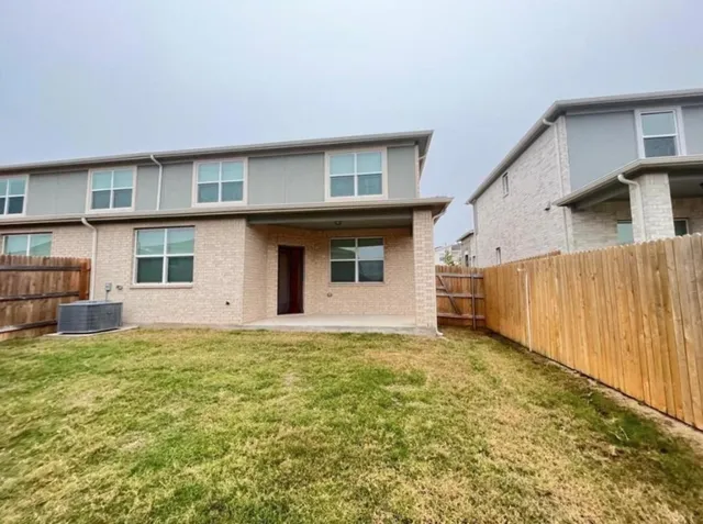 a view of a refrigerator in kitchen and an empty room with wooden floor