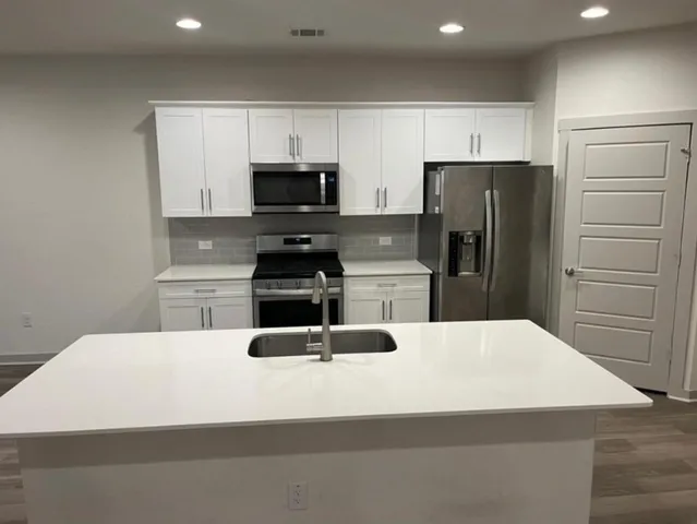 a kitchen with stainless steel appliances a refrigerator a sink a stove a microwave and wooden cabinets