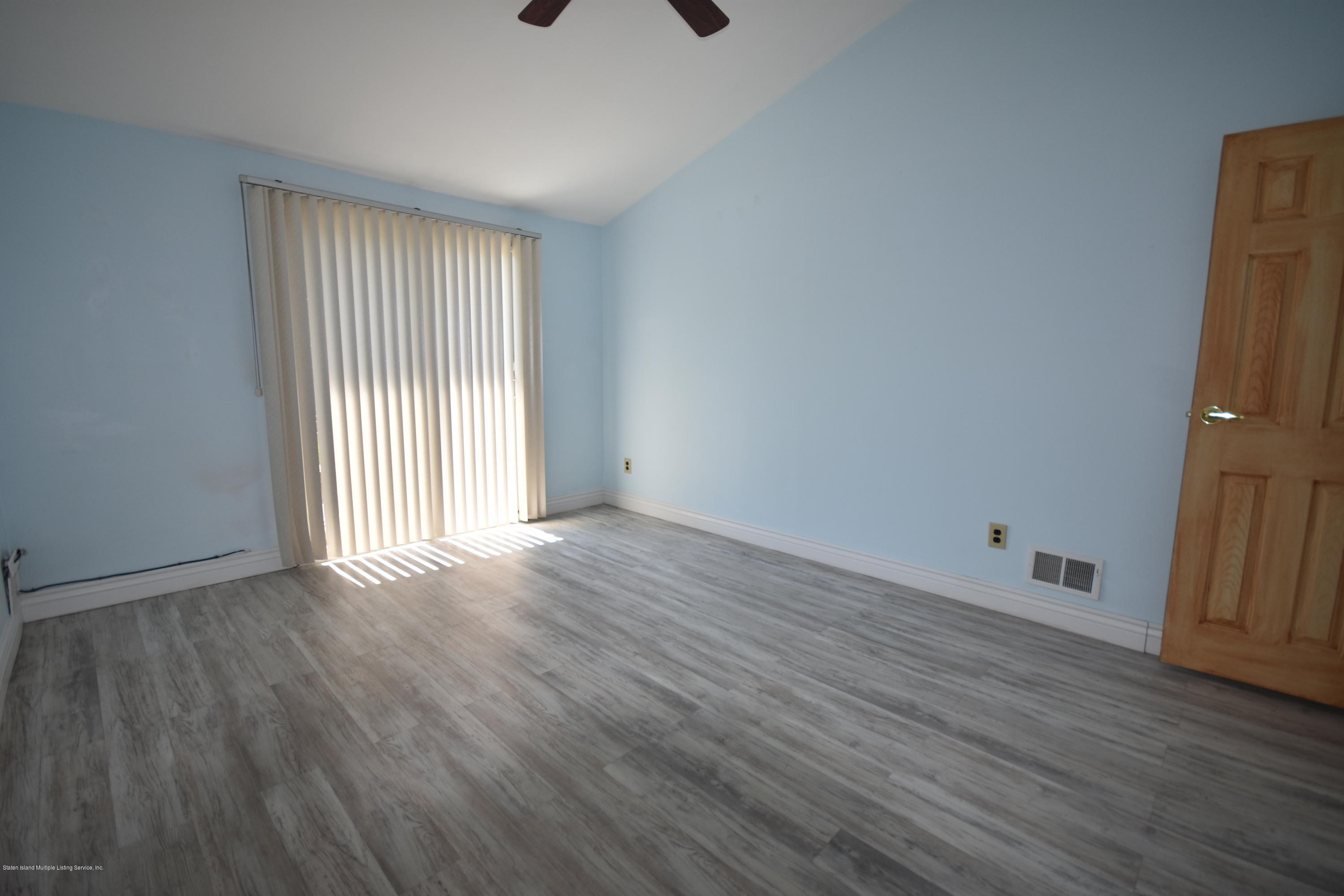 1726 Forest Hill Road Staten Island, NY 10314 - Photo 7 of 12 an empty room with wooden floor and windows