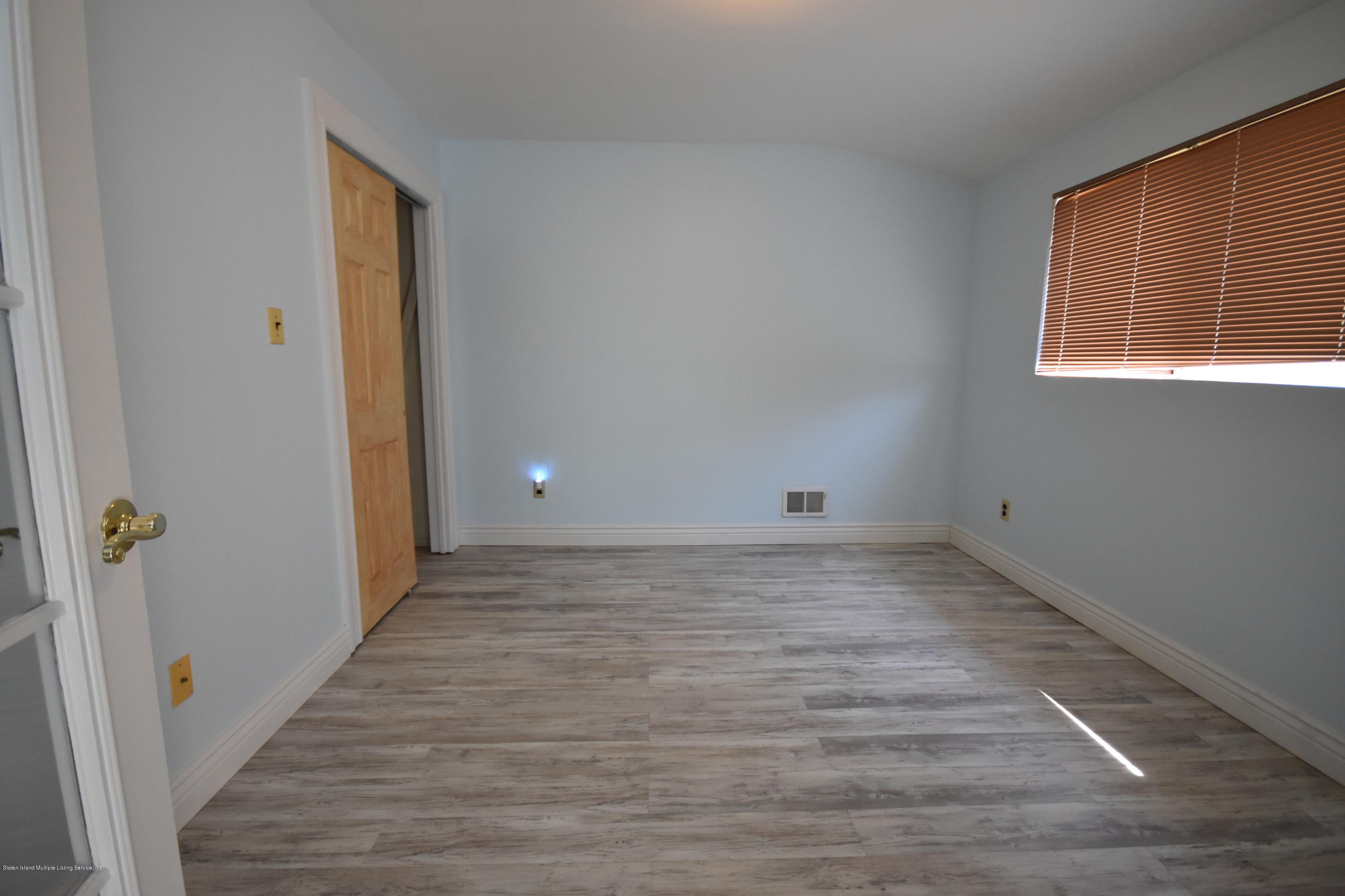 1726 Forest Hill Road Staten Island, NY 10314 - Photo 8 of 12 a view of a hallway with wooden floor and a window