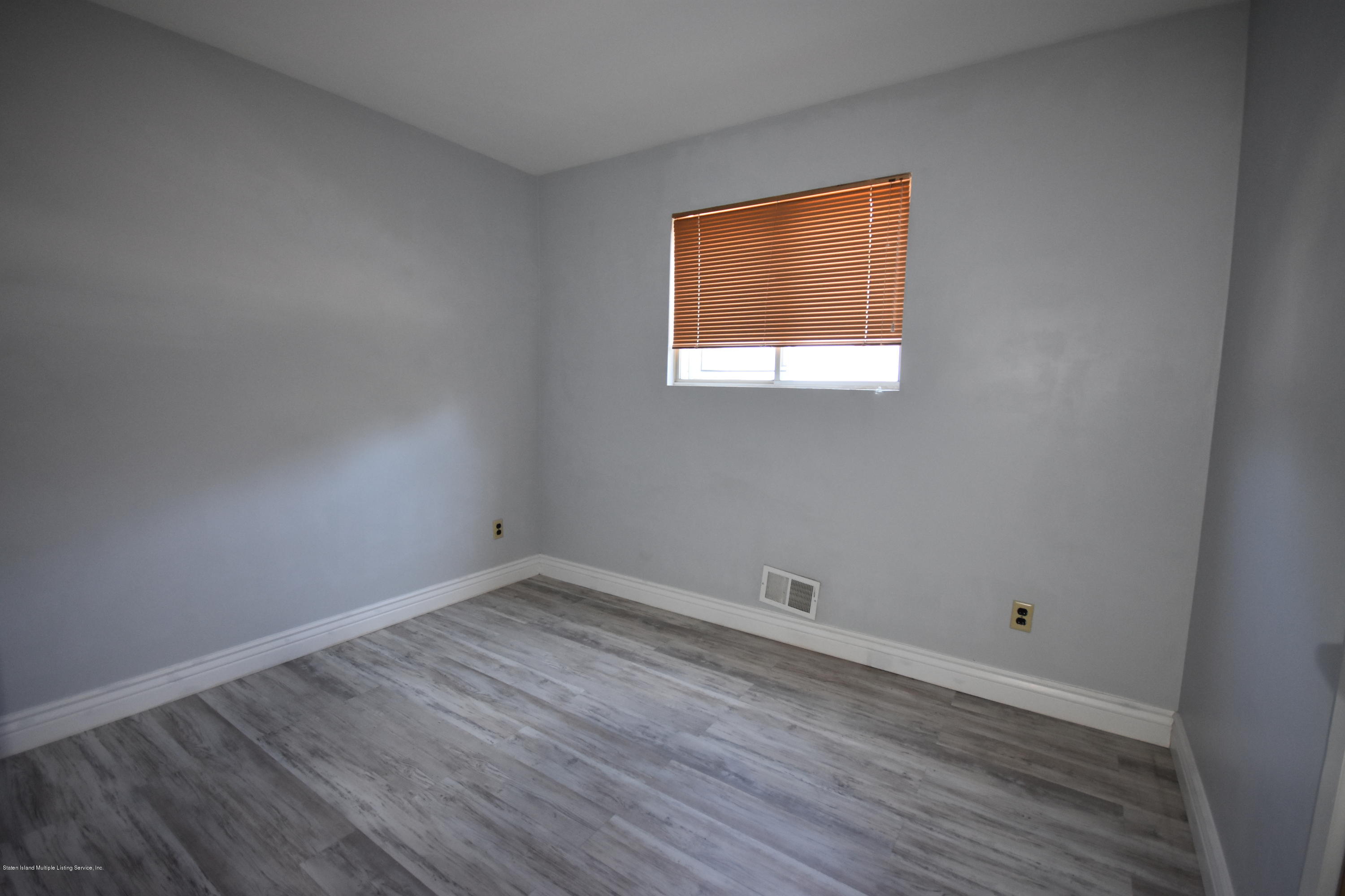 1726 Forest Hill Road Staten Island, NY 10314 - Photo 9 of 12 a view of an empty room with wooden floor and a window