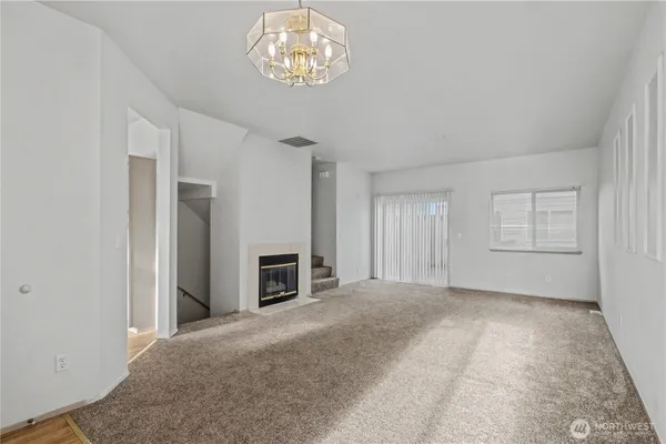 an empty room with a fireplace and chandelier
