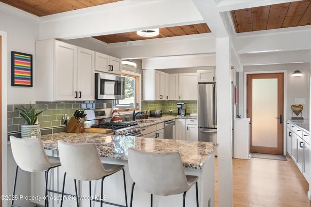 a kitchen with stainless steel appliances kitchen island granite countertop a refrigerator and a stove top oven