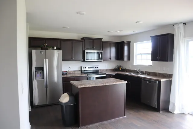 a kitchen with stainless steel appliances granite countertop a refrigerator stove microwave and sink