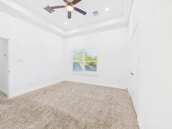 an empty room with windows and fan