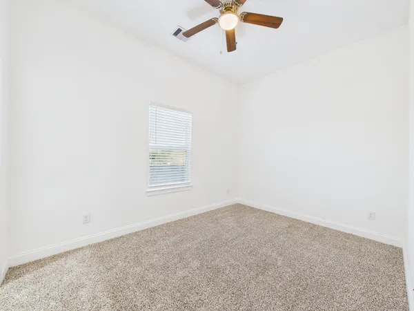 an empty room with a window and a fan