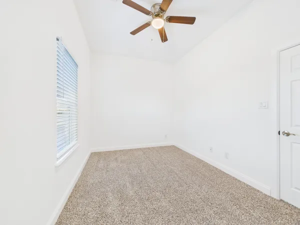 an empty room with a window and a fan