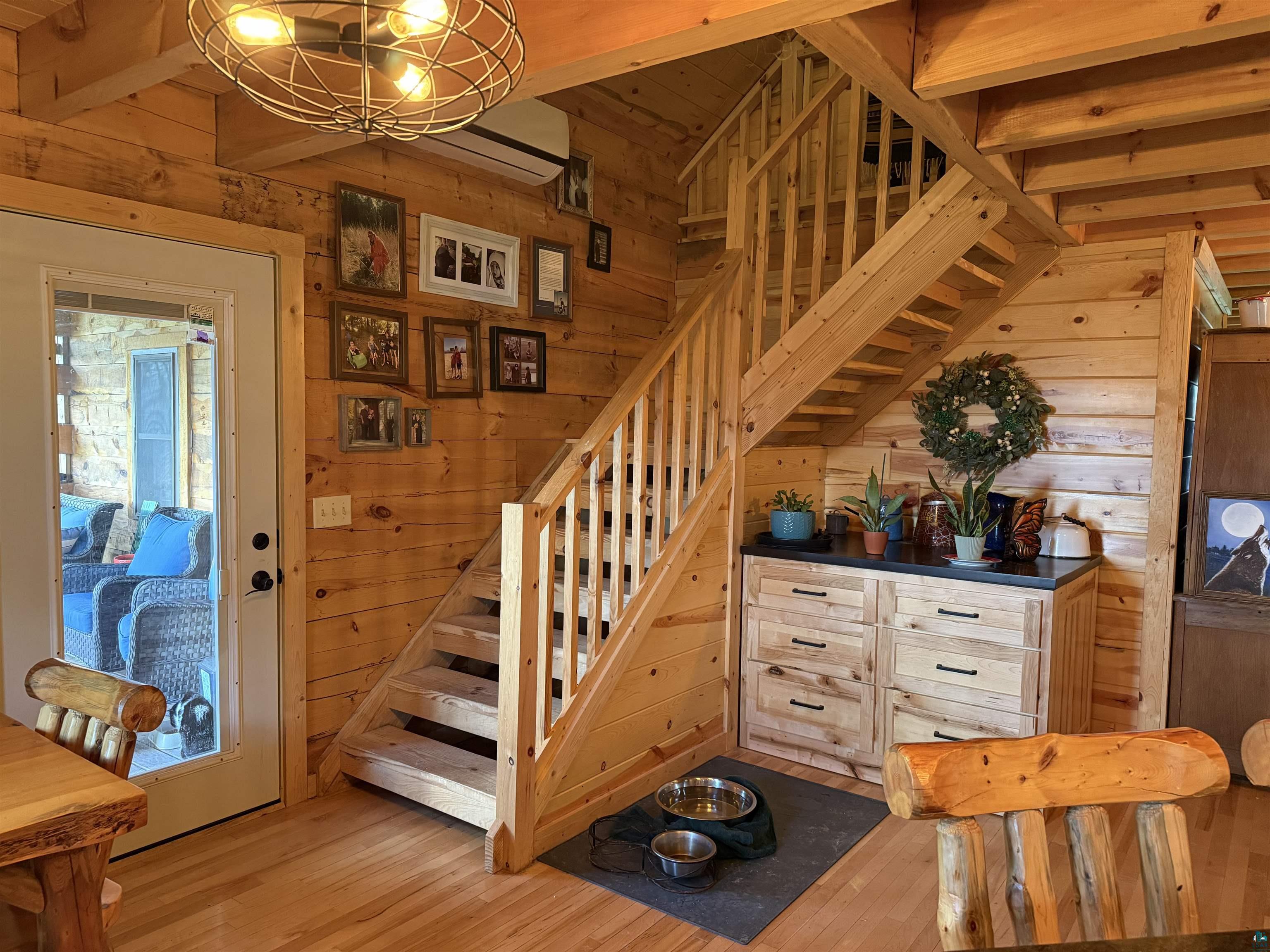 37590 Degerstrom Road Askov, MN 55704 - Photo 11 of 53 Natural wood staircase with matching railing, wood-finish flooring, and horizontal wood-paneled walls