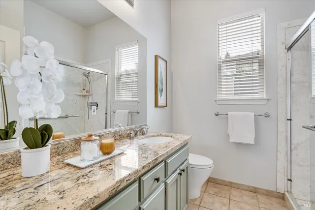 a bathroom with a granite countertop sink a toilet and a mirror