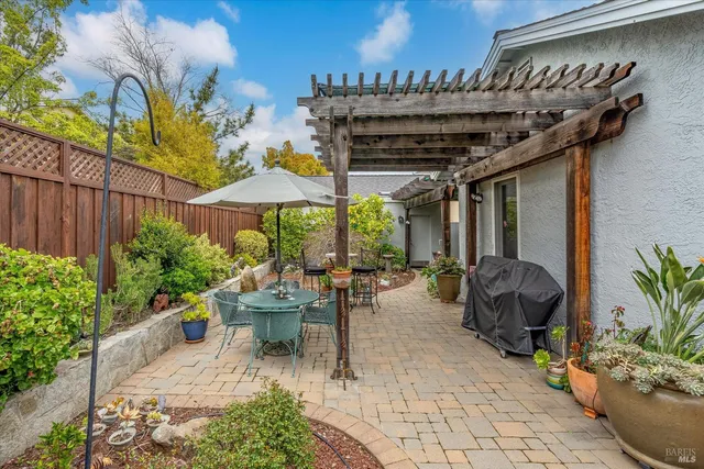a view of a patio with plants and chairs under an umbrella with potted plants
