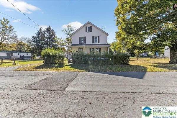 a front view of a house with a yard and trees