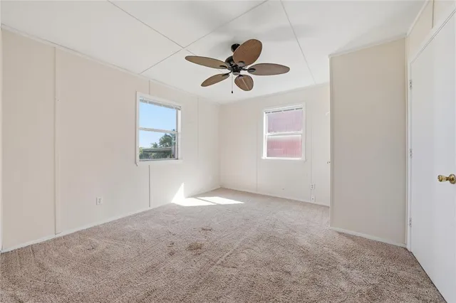an empty room with windows and fan