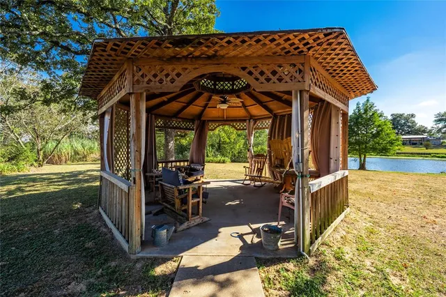 a view of a patio with wooden floor and roof with a garden