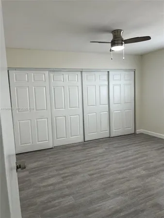 an empty room with wooden floor cabinet and windows