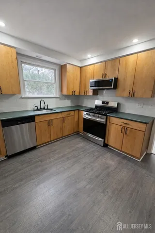 a large kitchen with granite countertop a stove top oven a sink a counter space and cabinets