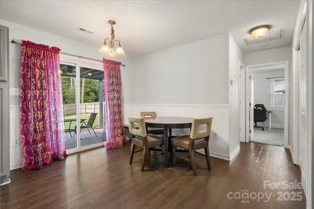 a dining room with wooden floor a chandelier a wooden table and chairs