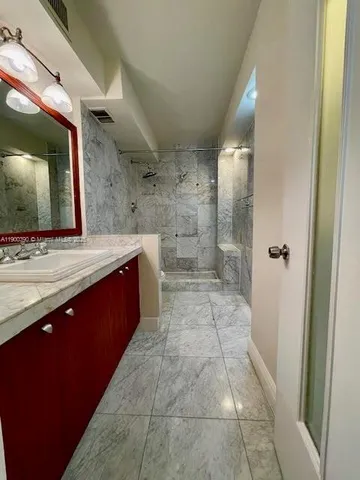 a spacious bathroom with a granite countertop sink a mirror and a shower