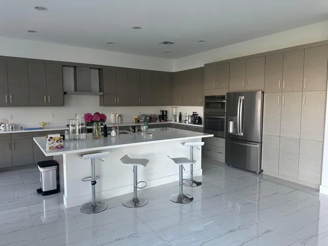 a kitchen with stainless steel appliances a sink a stove a refrigerator cabinets and chairs