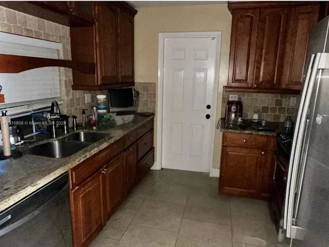 a kitchen with stainless steel appliances granite countertop a refrigerator and a sink