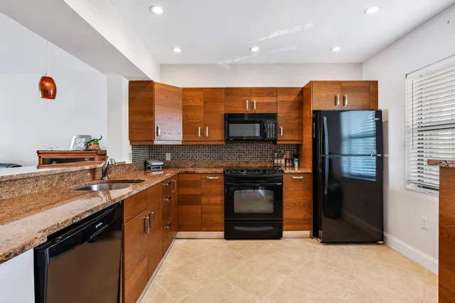 a kitchen with stainless steel appliances granite countertop a refrigerator a sink and a stove
