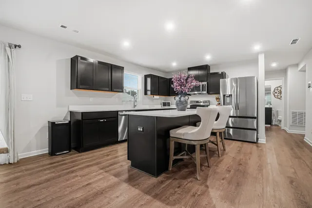 a kitchen with a sink a microwave a refrigerator and chairs