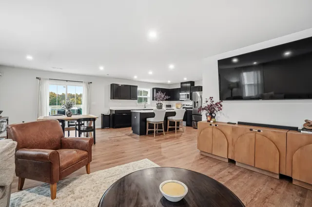 a living room with furniture kitchen view and a large window