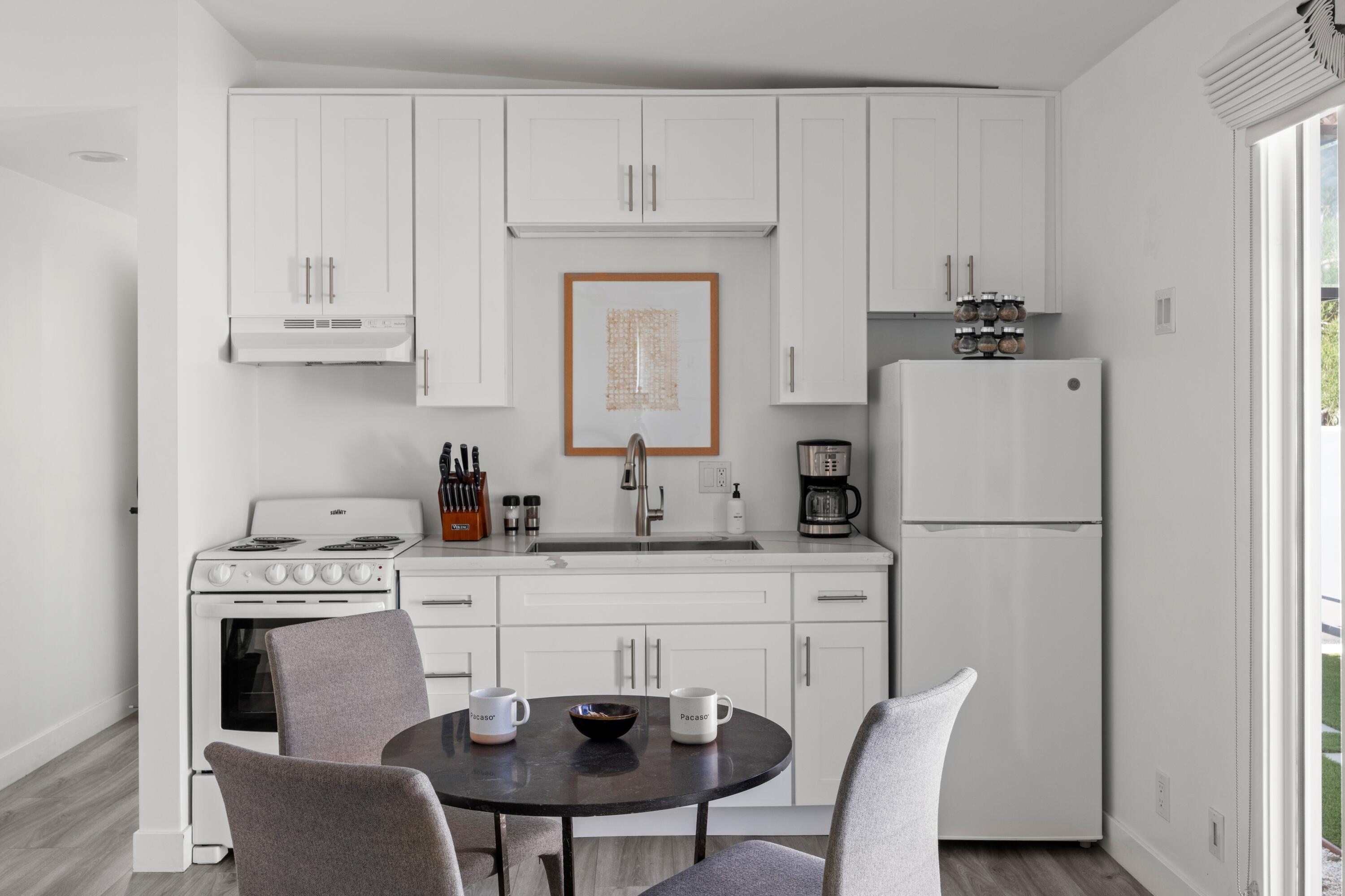 72870 Bel Air Road, Unit 3 Palm Desert, CA 92260 - Photo 9 of 35 a kitchen with stainless steel appliances a white refrigerator a stove a sink and white cabinets with wooden floors
